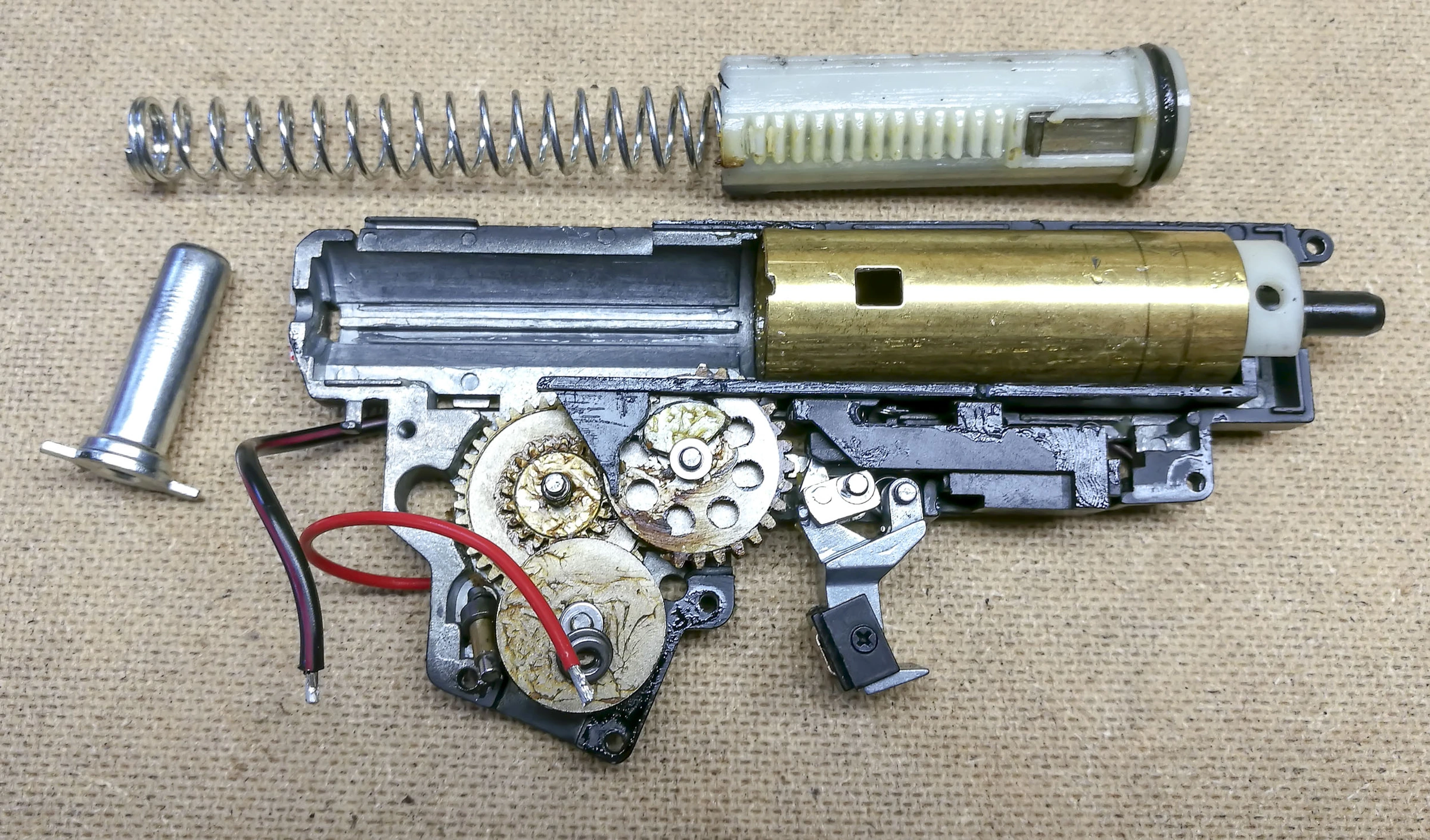 Opened JG AU-2G gearbox showing the gears, spring, piston, and cylinder.